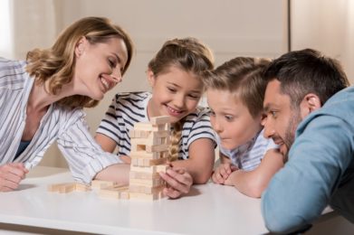 smiling family playing Jenga game at home together